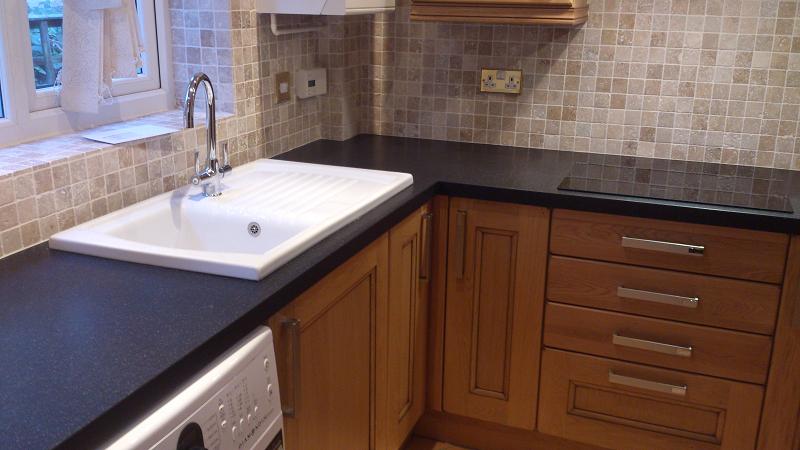 Dales Knotty Oak kitchen fitted with Encore worktops, travertine wall tiles and terracotta floor tiles